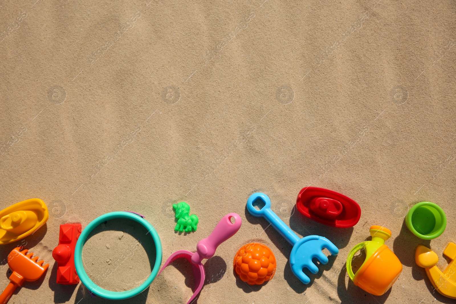 Photo of Set of plastic beach toys on sand, flat lay with space for text. Outdoor play