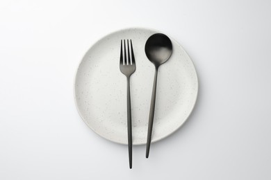 Photo of Plate, fork and spoon on white background, top view