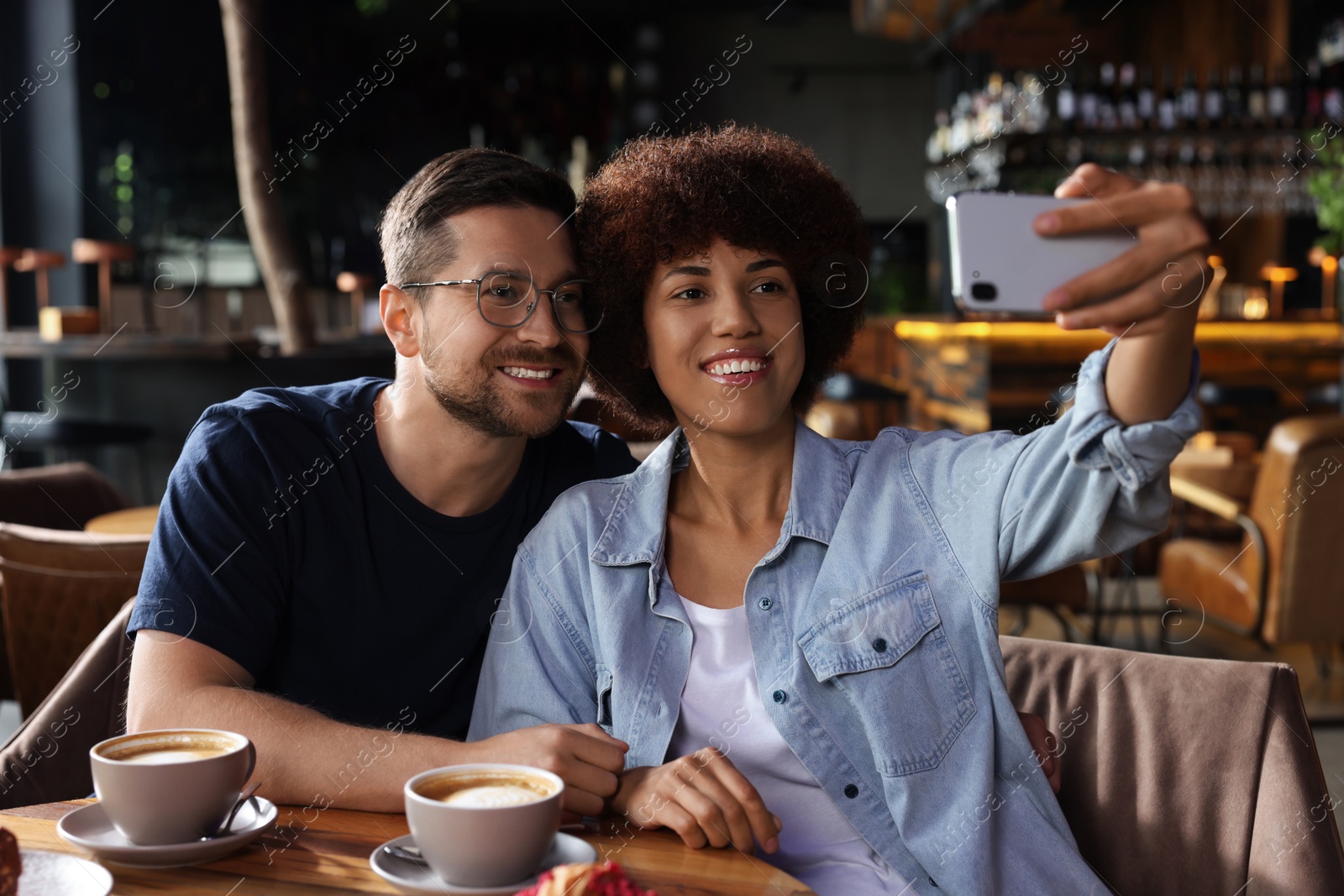 Photo of International dating. Happy couple taking selfie in cafe