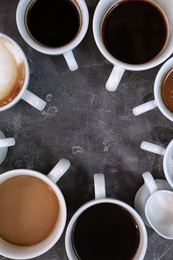 Cups of fresh aromatic coffee on grey background, top view