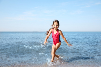 Photo of Cute little child having fun in sea on sunny day. Beach holiday