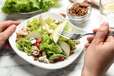 Photo of Woman with tasty pear salad at white marble table, closeup
