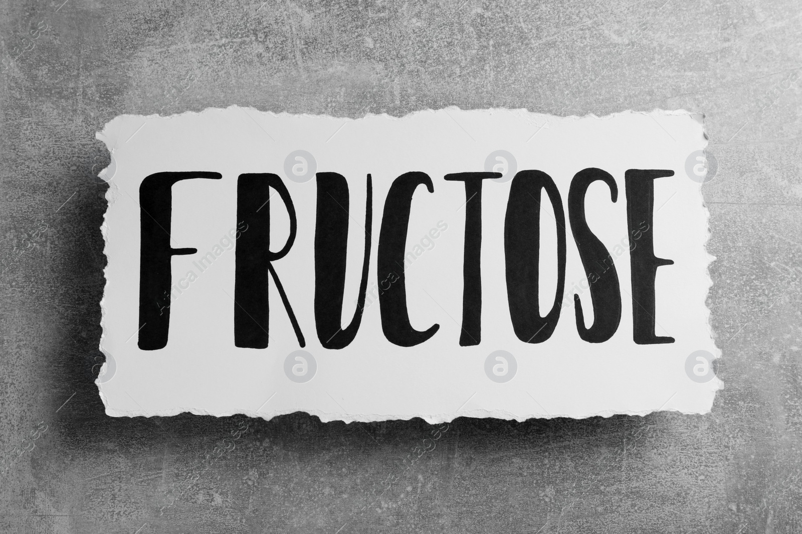 Photo of Paper sheet with word Fructose on grey table, top view