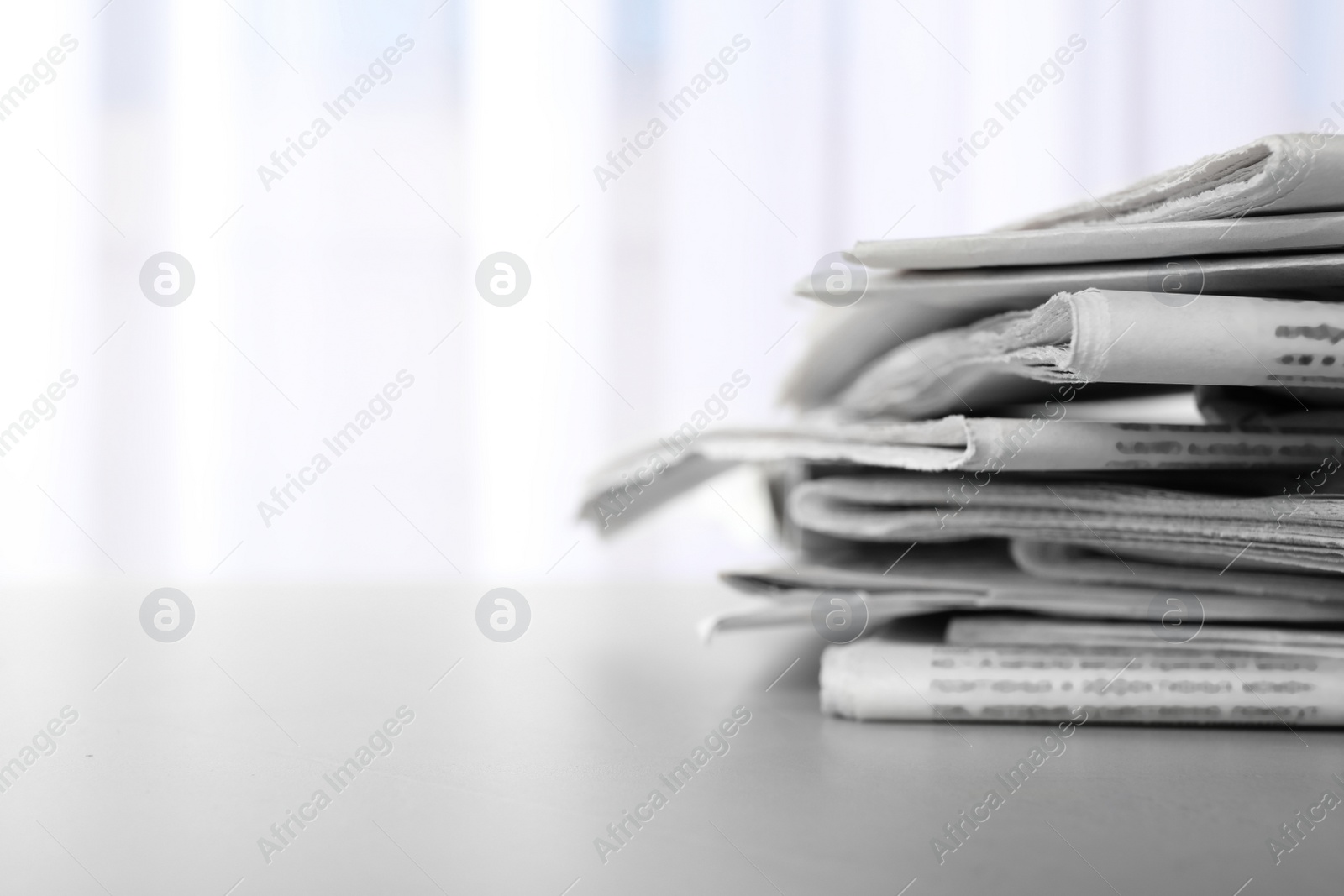 Photo of Pile of newspapers on grey table, space for text. Journalist's work
