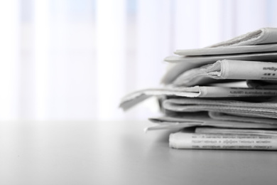 Photo of Pile of newspapers on grey table, space for text. Journalist's work