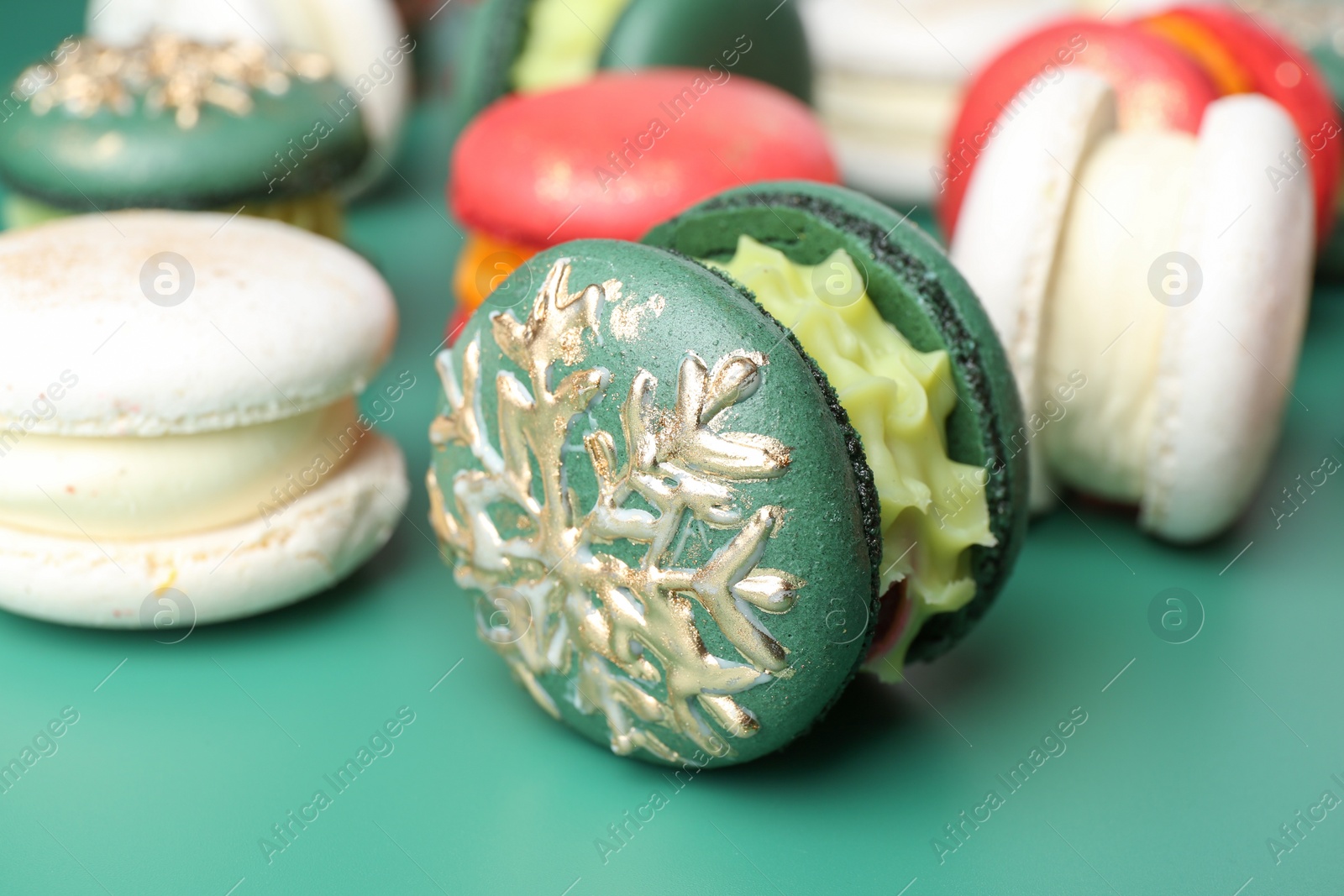 Photo of Beautifully decorated Christmas macarons on green background, closeup