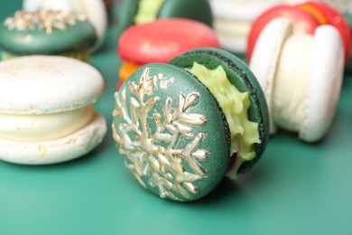 Beautifully decorated Christmas macarons on green background, closeup