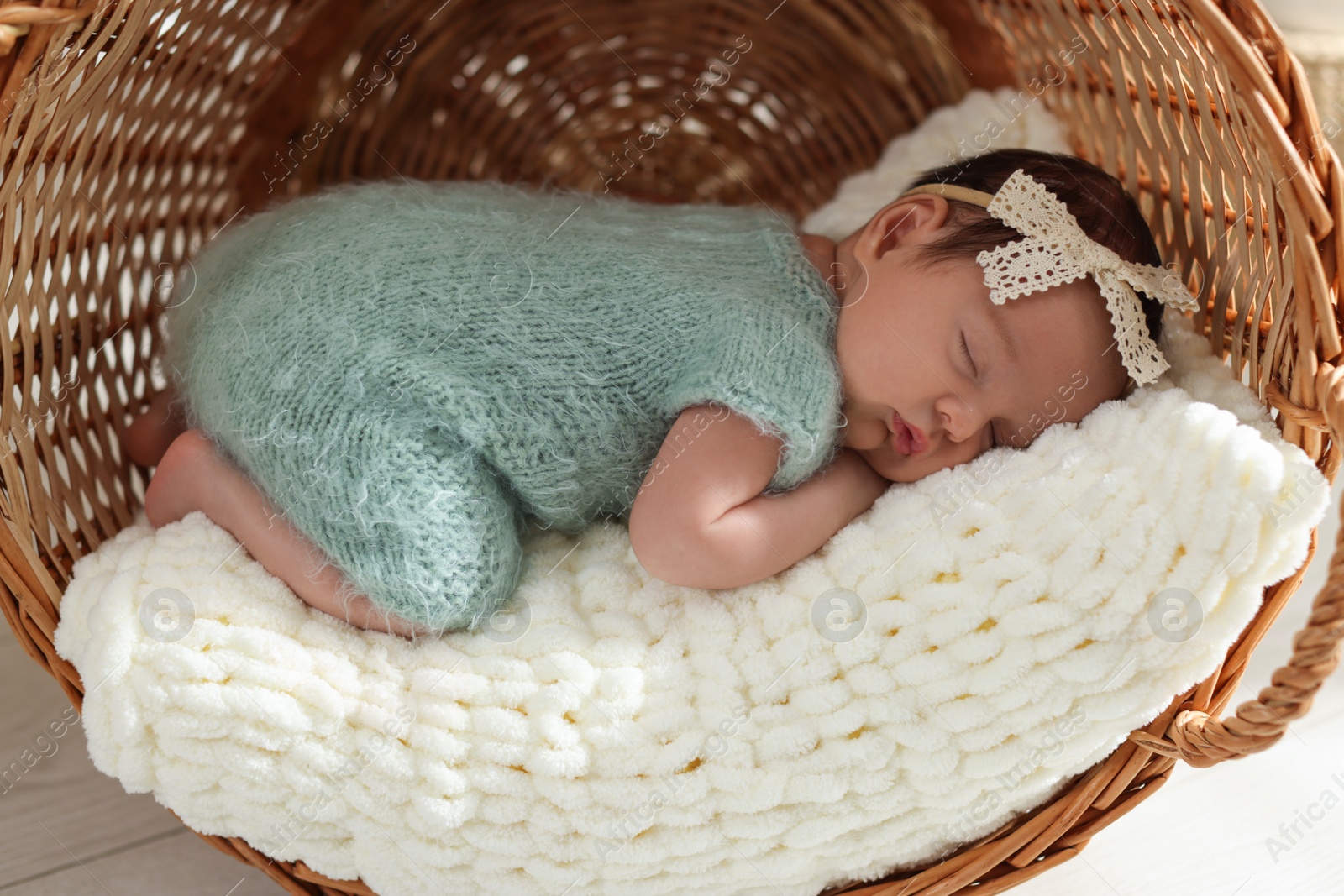 Photo of Adorable newborn baby sleeping in wicker basket with soft plaid