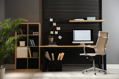 Photo of Comfortable workplace with computer and office chair. Stylish room interior