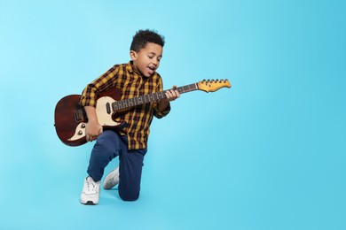 Photo of African-American boy with electric guitar on turquoise background. Space for text