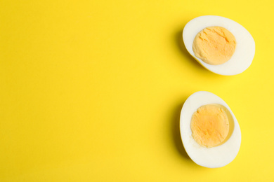 Photo of Halves of fresh hard boiled chicken egg on yellow background, flat lay. Space for text