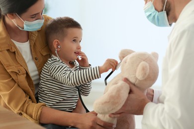 Photo of Mother and son visiting pediatrician in hospital. Doctor playing with little boy