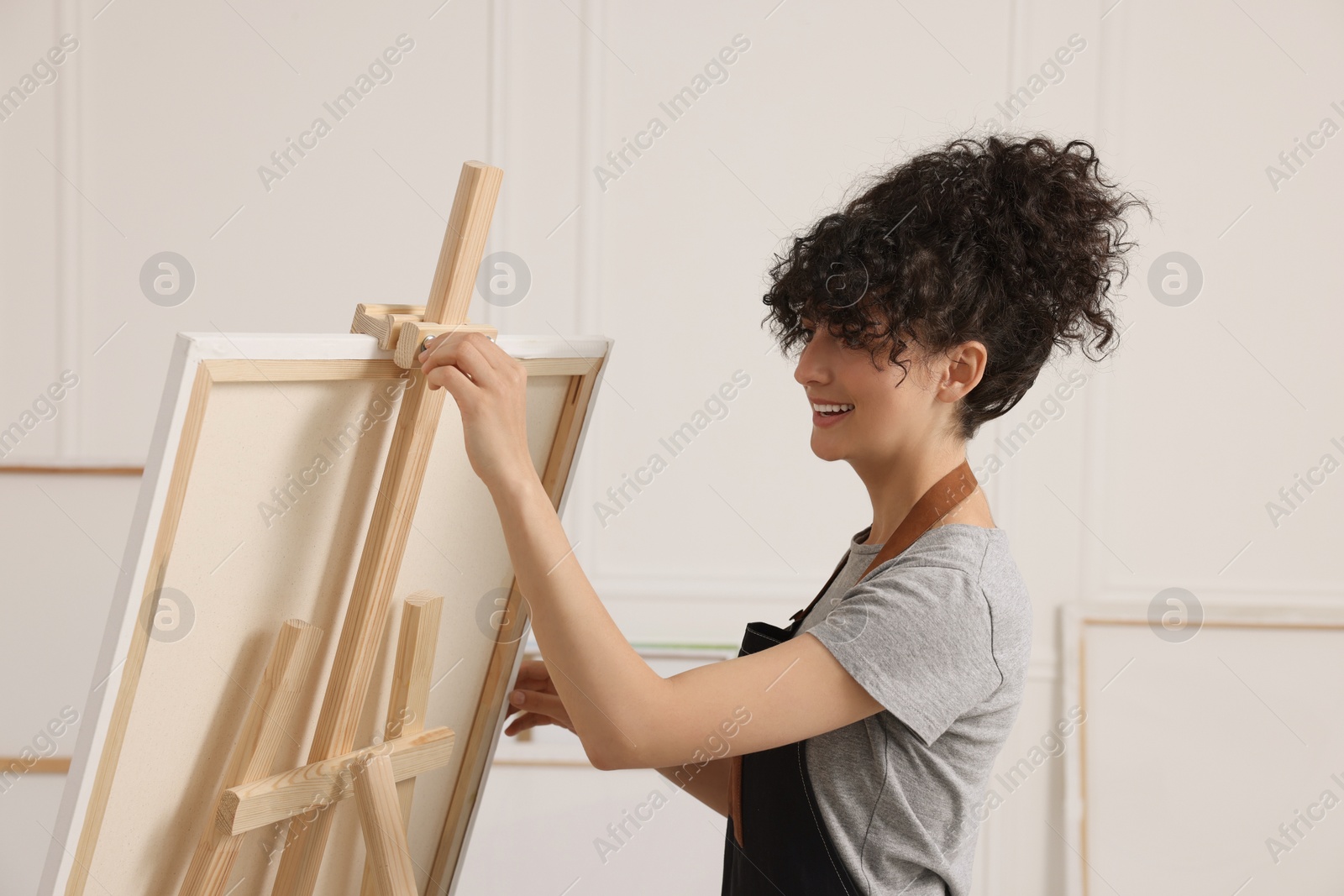 Photo of Young woman near wooden easel in studio