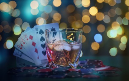 Image of Casino chips, cards and alcohol drink on table against blurred lights. Straight poker combination