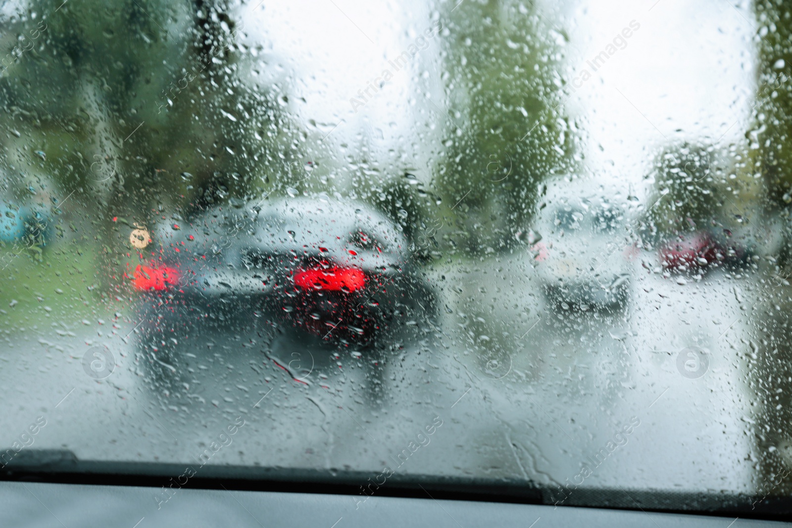 Photo of Blurred view of road through wet car window. Rainy weather