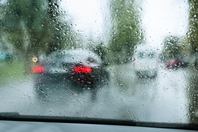 Blurred view of road through wet car window. Rainy weather