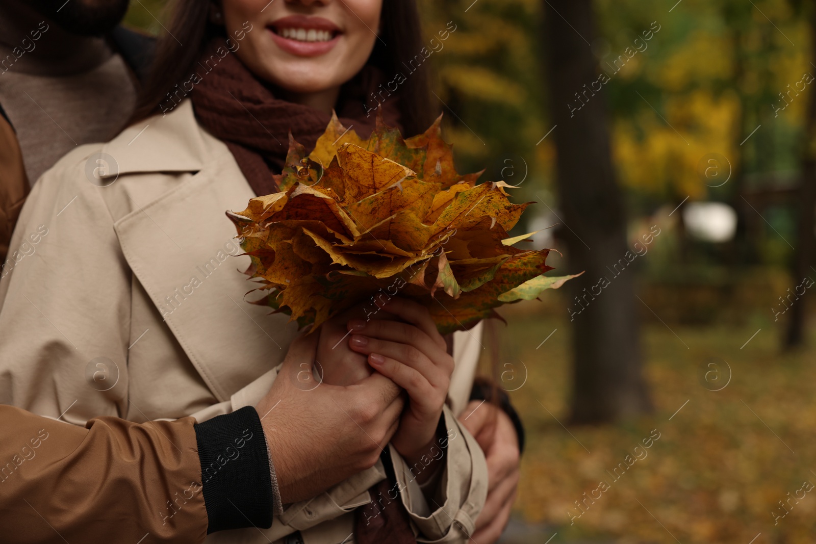 Photo of Happy young couple with dry leaves in autumn park, closeup. Space for text