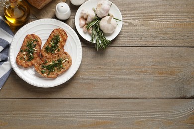 Photo of Tasty bruschettas with oil and garlic on wooden table, flat lay. Space for text