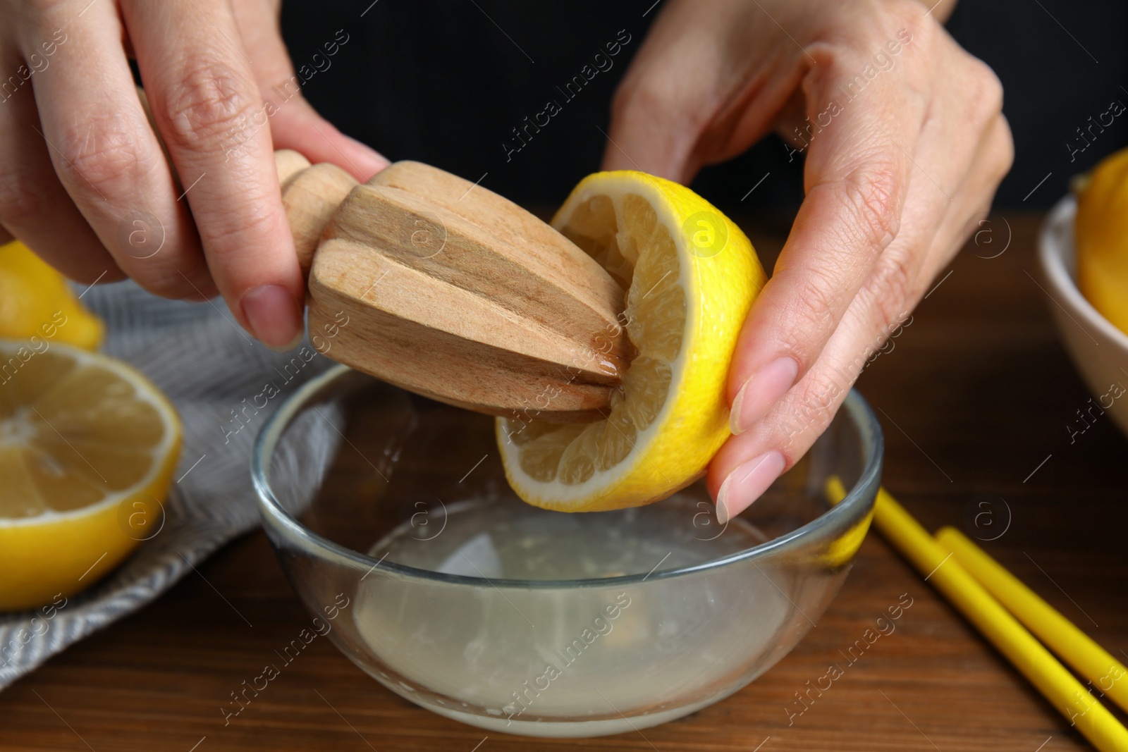 Photo of Woman squeezing lemon juice with citrus reamer at wooden table, closeup