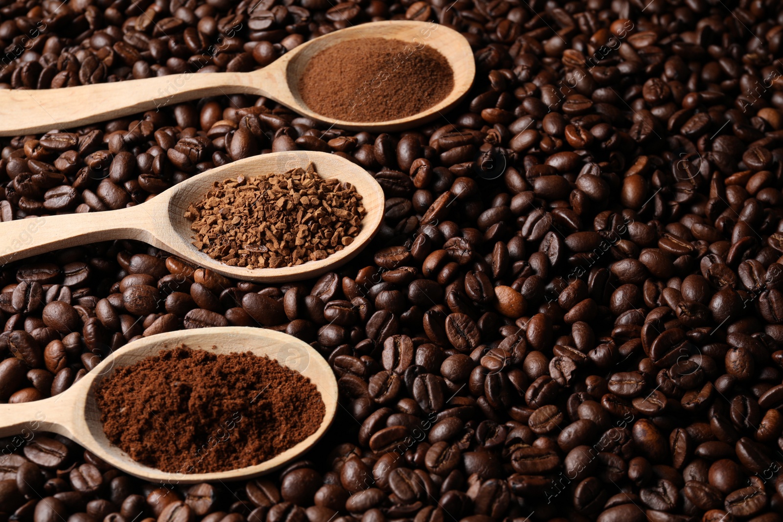 Photo of Spoons with different types of coffee on roasted beans. Space for text