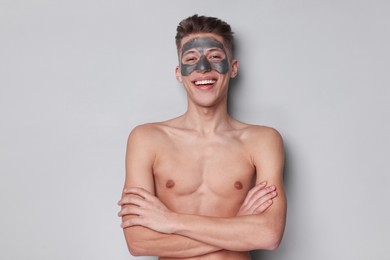 Handsome man with clay mask on his face against light grey background