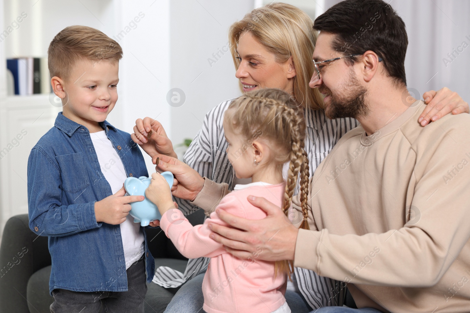 Photo of Family budget. Children and their parents putting coins into piggy bank indoors