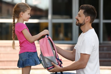 Photo of Happy father preparing his daughter to school outdoors