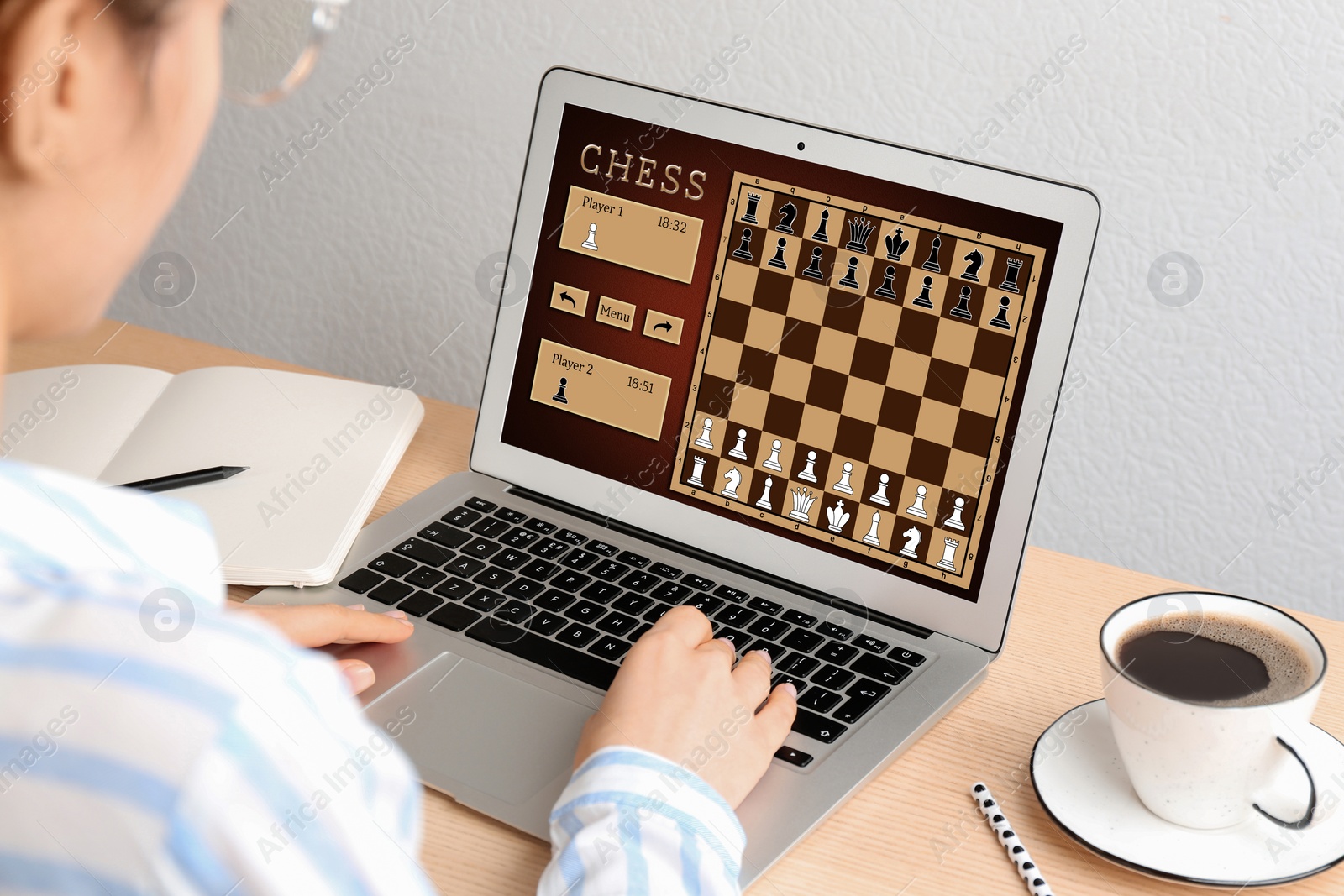 Image of Woman playing online chess on laptop at table, closeup