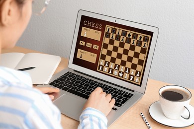 Woman playing online chess on laptop at table, closeup