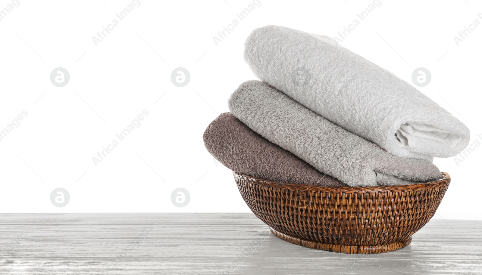 Photo of Fresh towels on wooden table against white background. Space for text