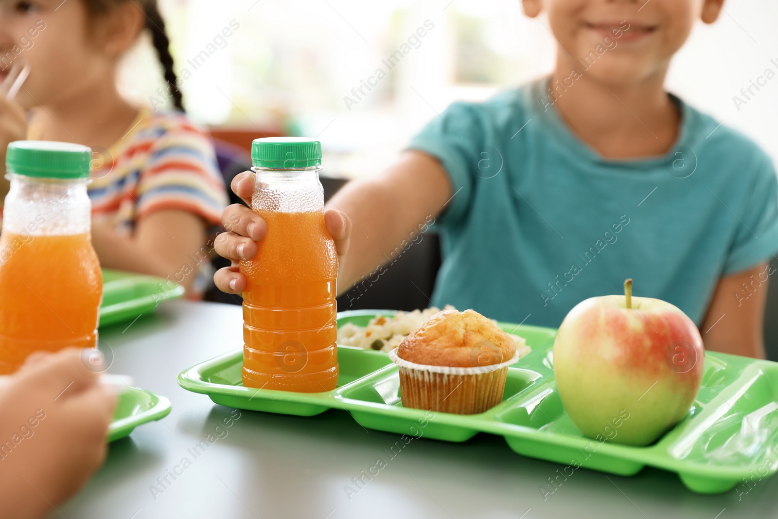 Photo of Children sitting at table and eating healthy food during break at school, closeup