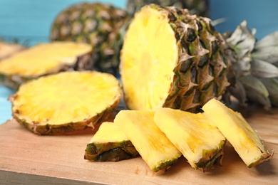 Photo of Cut fresh juicy pineapple on wooden board, closeup