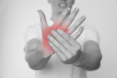 Man suffering from pain in wrist, closeup. Black and white effect