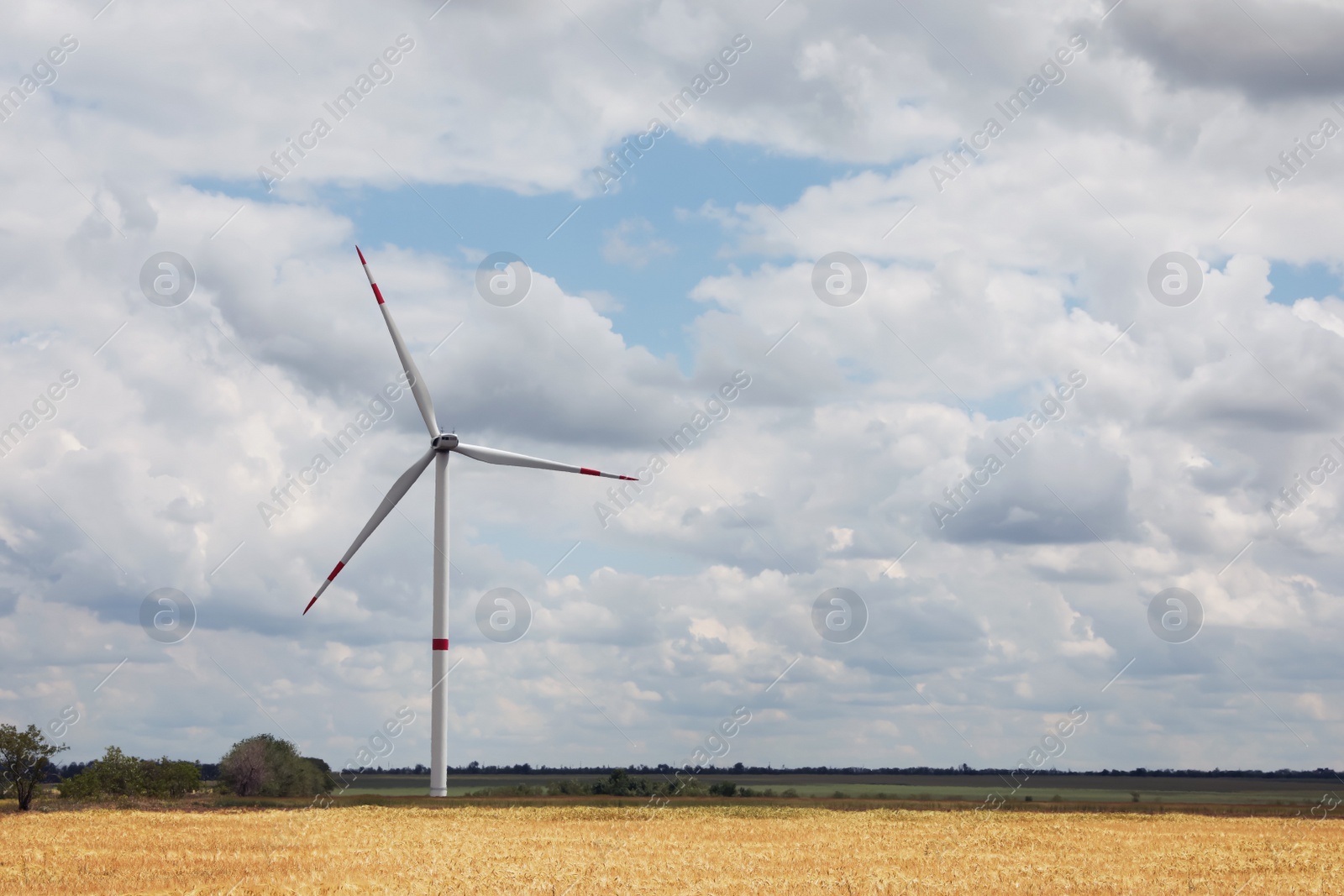 Photo of Modern wind turbine in field on cloudy day. Alternative energy source