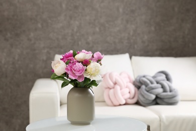 Photo of Vase with bouquet of beautiful peonies on table in room, space for text