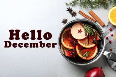 Image of Hello December greeting card. Saucepan with tasty mulled wine on table, flat lay