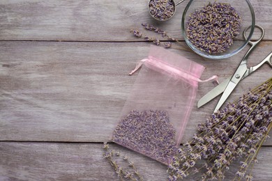 Scented sachet with dried lavender flowers and scissors on wooden table, flat lay. Space for text