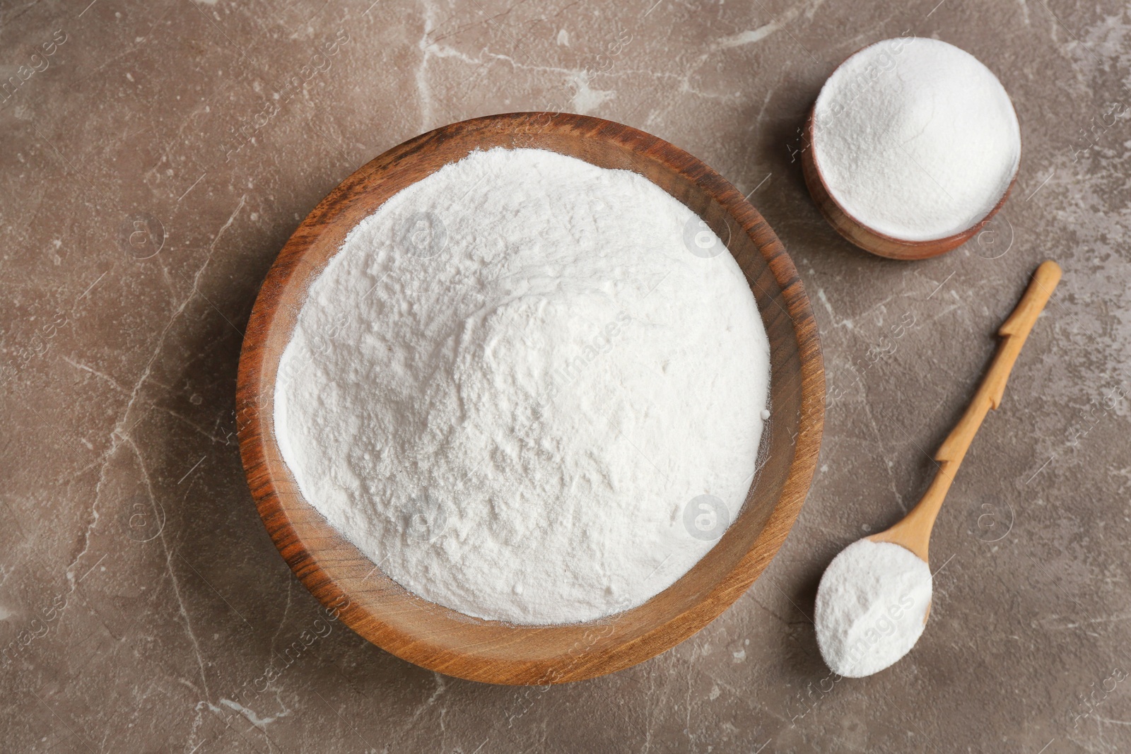 Photo of Bowls and spoon with baking soda on gray table, top view