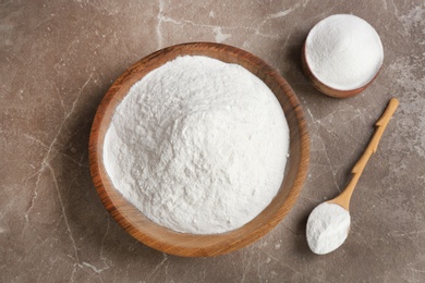 Photo of Bowls and spoon with baking soda on gray table, top view