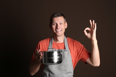 Happy man with cooking pot on brown background