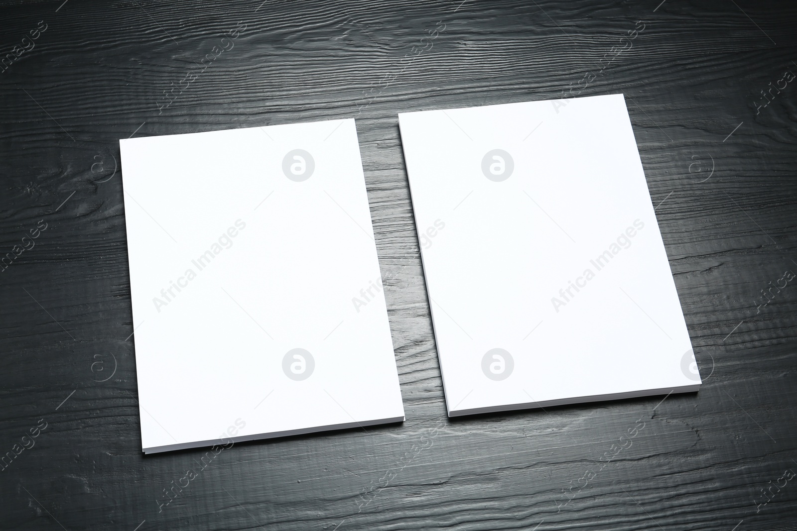 Photo of Blank paper sheets for brochure on black wooden background. Mock up