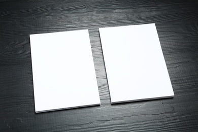 Blank paper sheets for brochure on black wooden background. Mock up
