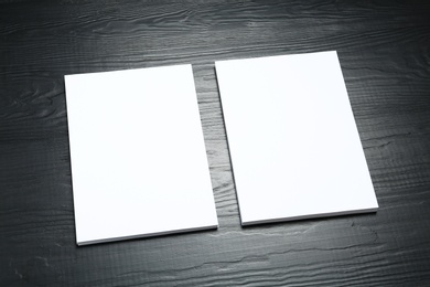 Photo of Blank paper sheets for brochure on black wooden background. Mock up