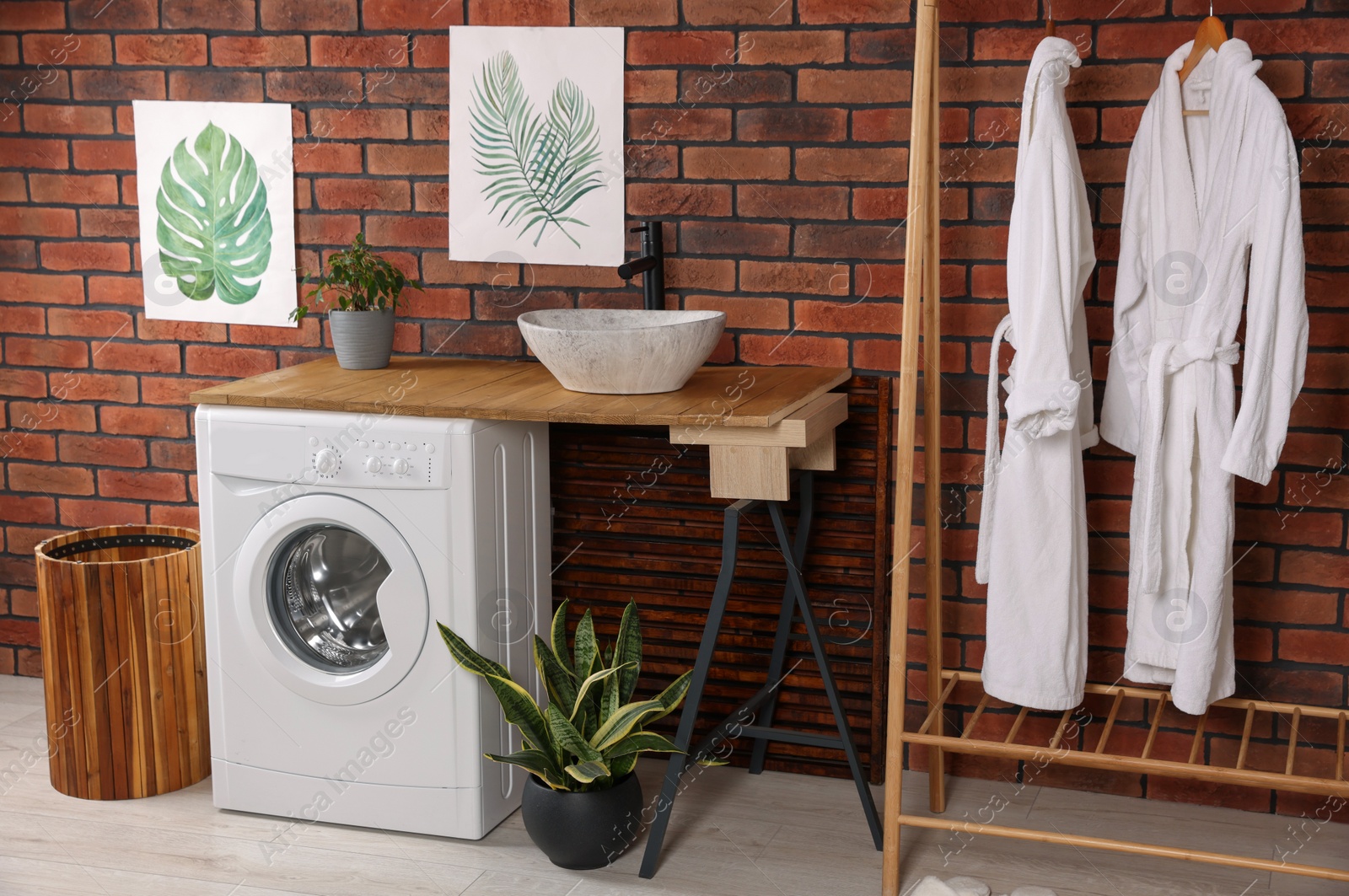 Photo of Washing machine and wooden rack with terry bathrobes indoors. Laundry room interior design