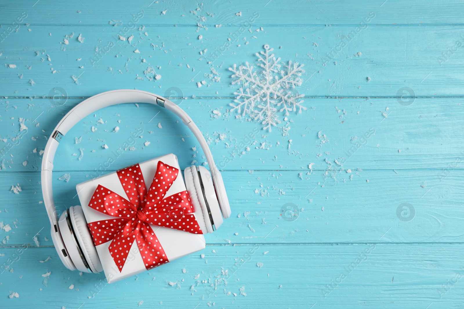 Photo of Modern headphones and gift box on blue wooden background, top view with space for text. Christmas music concept