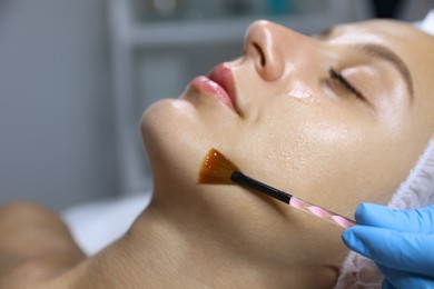 Photo of Young woman during face peeling procedure in salon, closeup