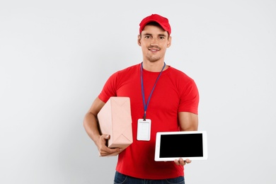 Photo of Happy young courier with tablet and parcel on white background