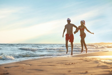 Happy couple with Santa hats together on beach. Christmas vacation