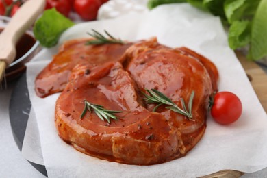 Photo of Raw marinated meat and rosemary on light table, closeup