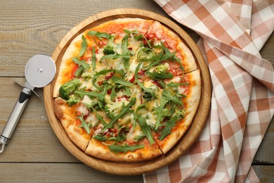 Photo of Board with delicious vegetarian pizza on wooden table, top view